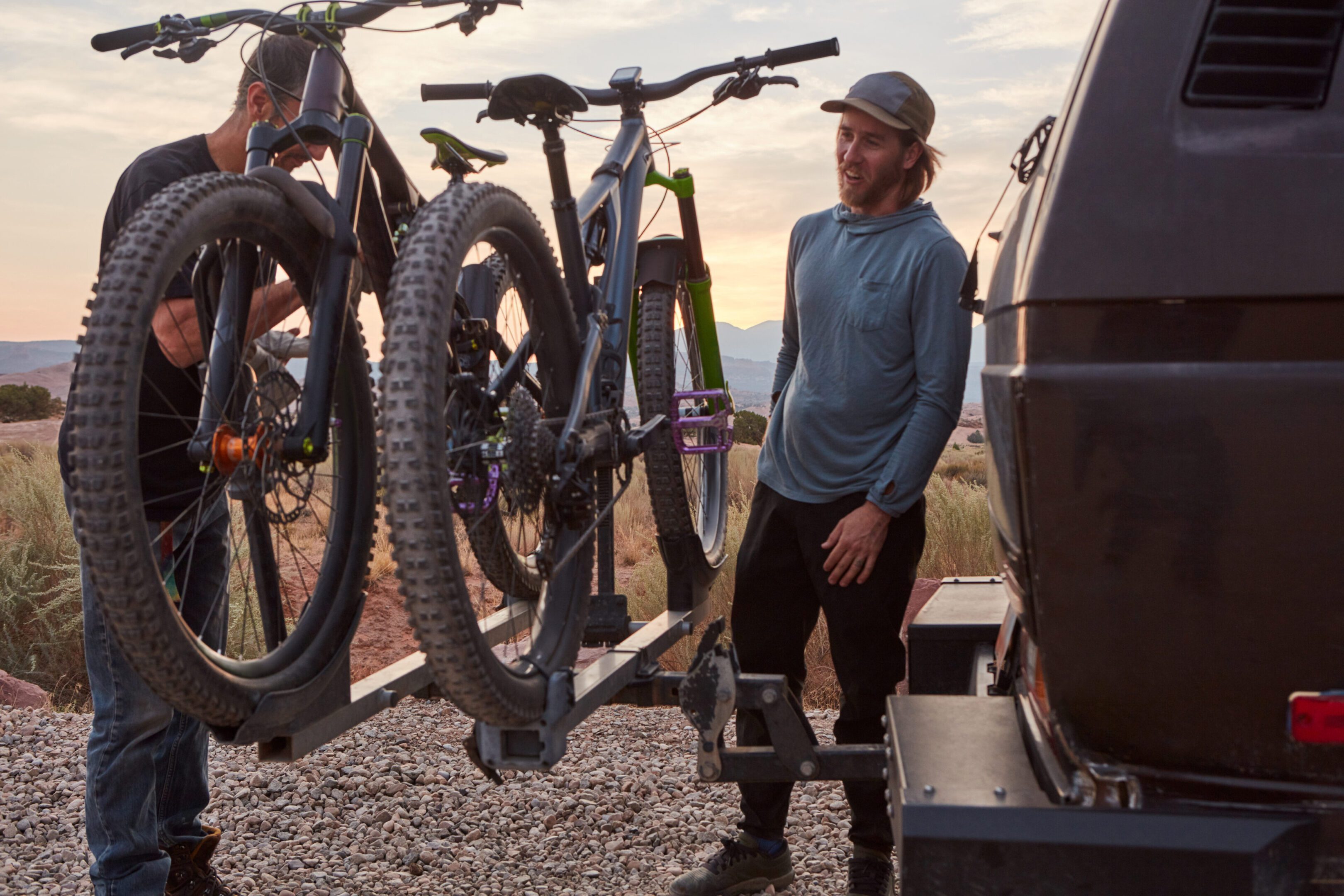 A man standing next to two bikes on the side of a road.